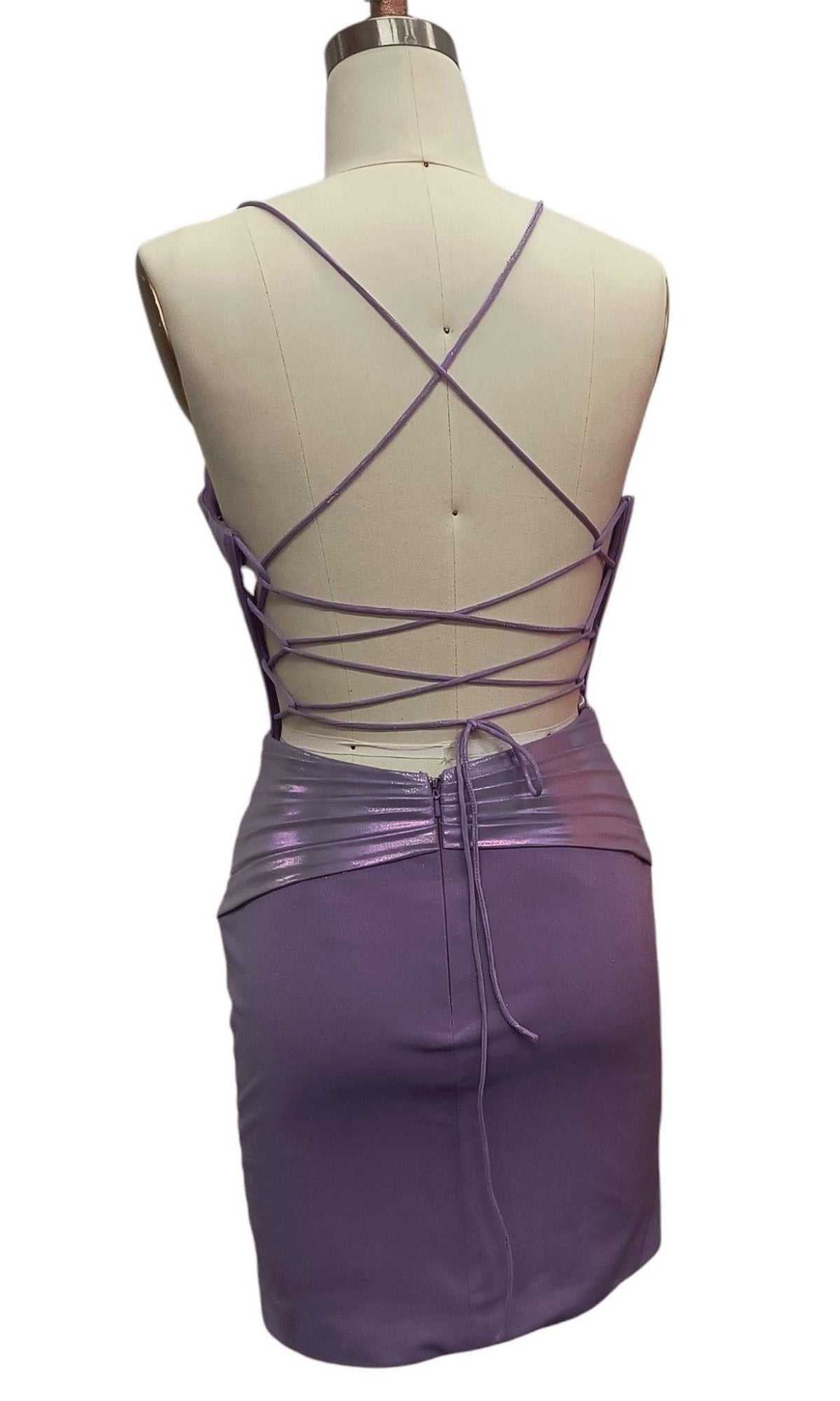 Back view of the Short Corset Hoco Dress: 12386 in purple, featuring cut-out details, crisscross straps, and a ruched shiny waistband displayed on a dress form.